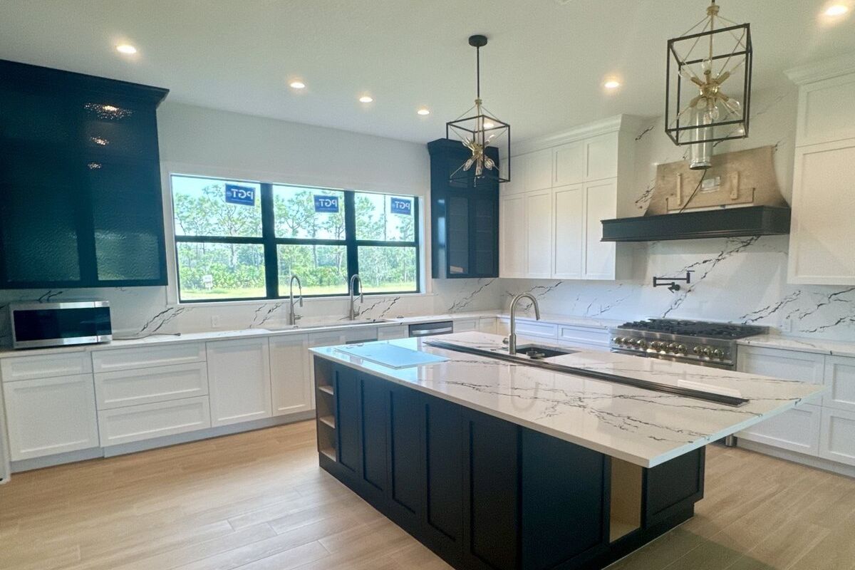 Remodeled kitchen with a navy island, quartz waterfall counter and lantern pendants