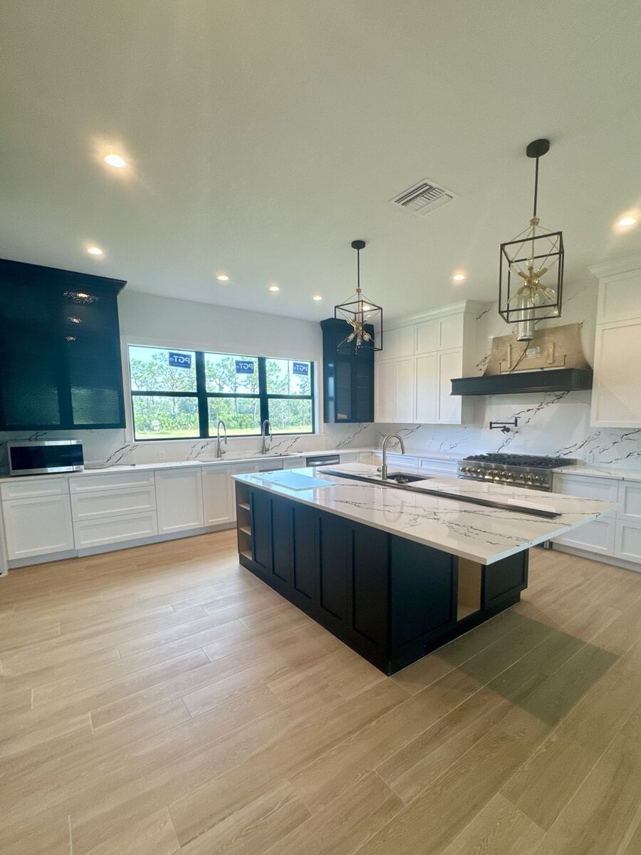 Kitchen with a navy island, quartz counters and a marble-look backsplash