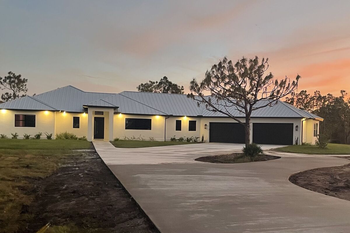 Single-story custom home at dusk with soffit lighting and a metal roof
