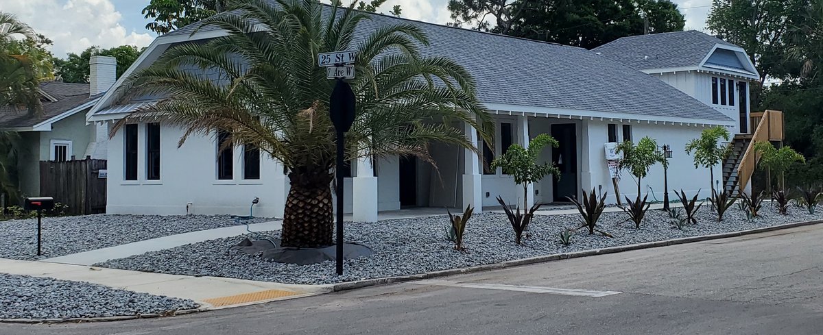 Coastal bungalow with a paver drive and mature palms