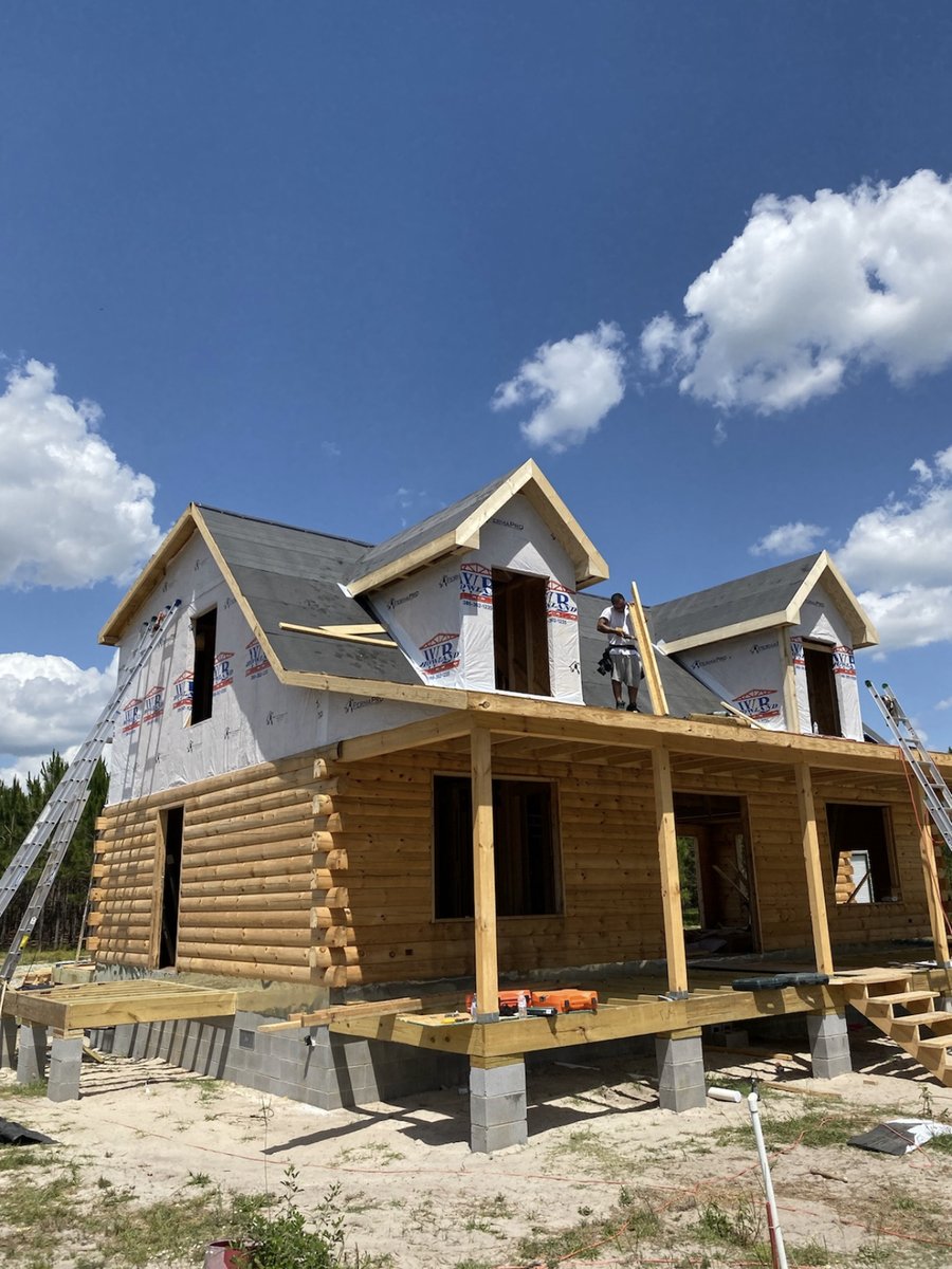 Two-story home under construction with framed porch posts
