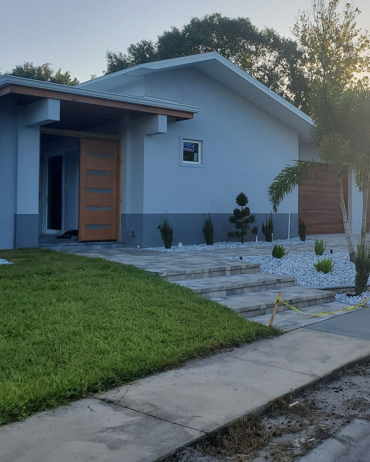 Contemporary home entry with a wood pivot door, smooth stucco and stone landscaping
